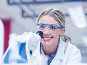 Estudiante con bata de laboratorio personalizada usando microscopio