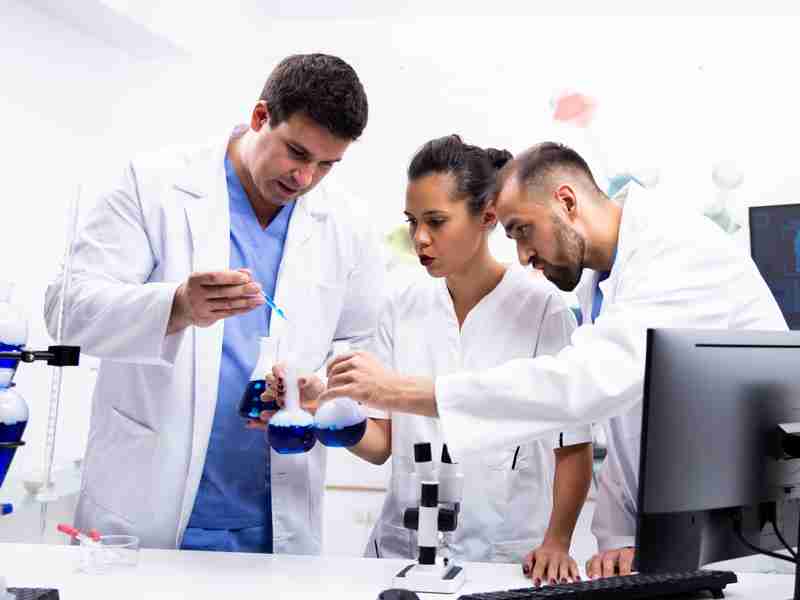Equipo de estudiantes con batas personalizadas trabajando en laboratorio