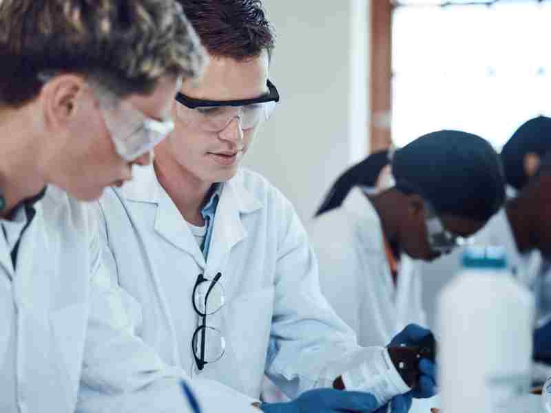 Estudiantes universitarios con batas personalizadas en clase de laboratorio
