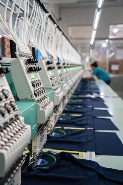 Máquina de bordado industrial personalizando prendas en taller de Bordagran